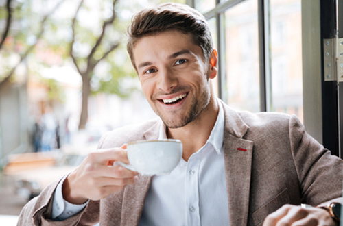 コーヒーを片手に笑顔の男