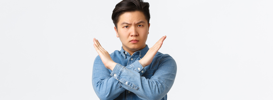 胸元で×マークを作る男性