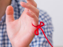 小指に赤い糸が結ばれている男性