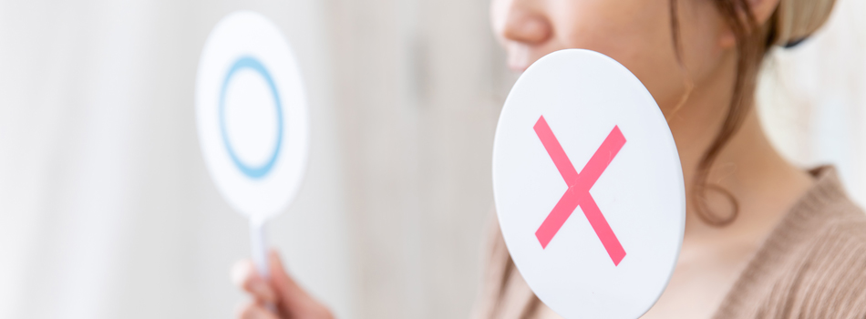 〇マークと、×マークを両手に持っている女性