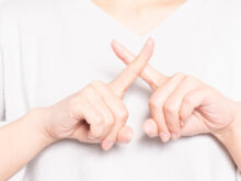 指で×を作る女性