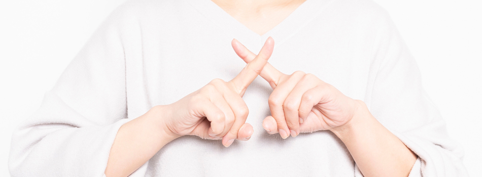 指で×を作る女性