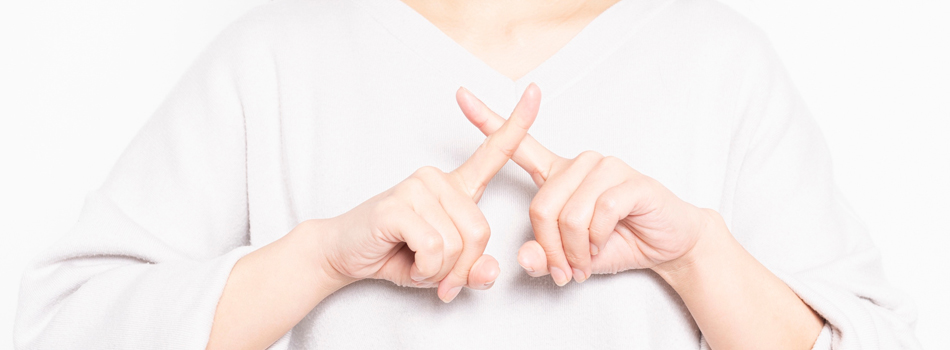 指でバツを作る女性