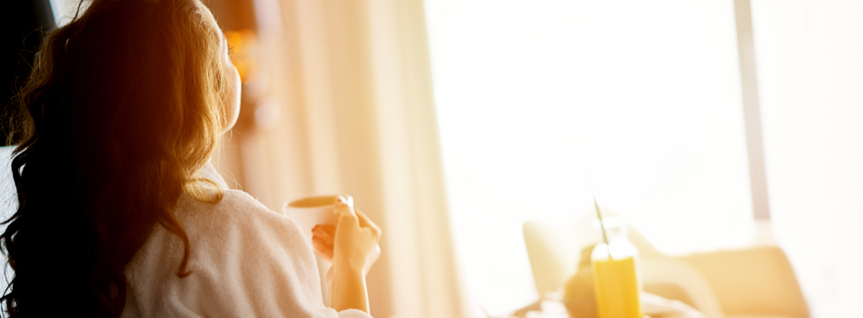 家で一人、夕暮れを見ている女性