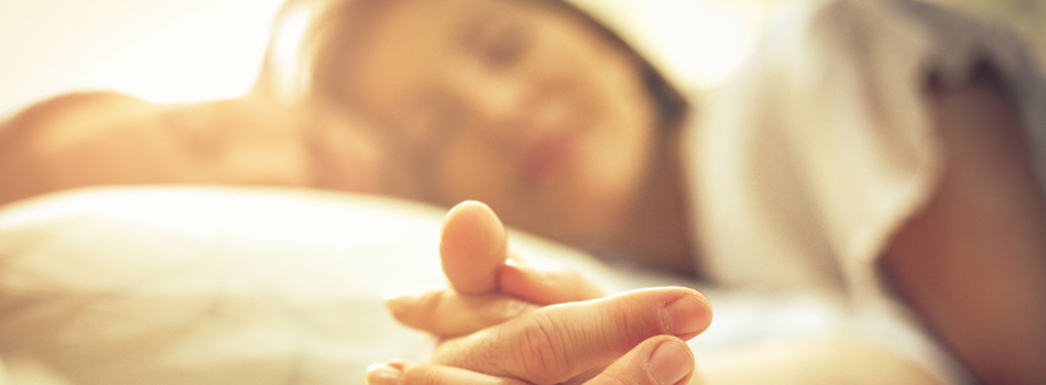 ベッドの上で手を繋ぐ男女