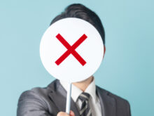 ×マークを持ったスーツの男性