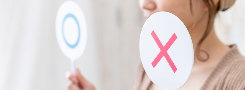 両手に〇と×の札を持つ女性