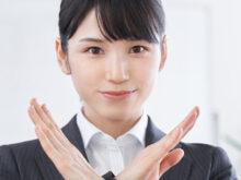 手で×マークを作る女性