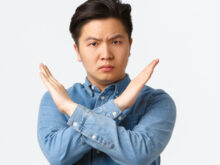 胸元で×マークを作る男性