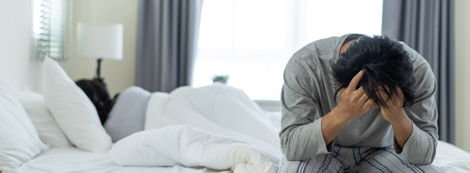 女性が寝ている横で頭を抱える男性