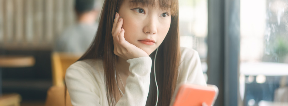 元気が無さそうにスマホを持っている女性