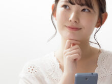 スマートフォンを持ち、何か考えている女性