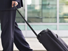 スーツケースを引くスーツの男性