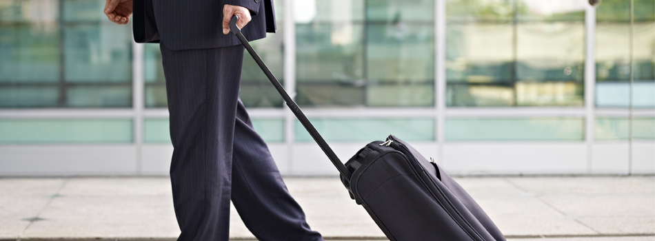 スーツケースを引くスーツの男性