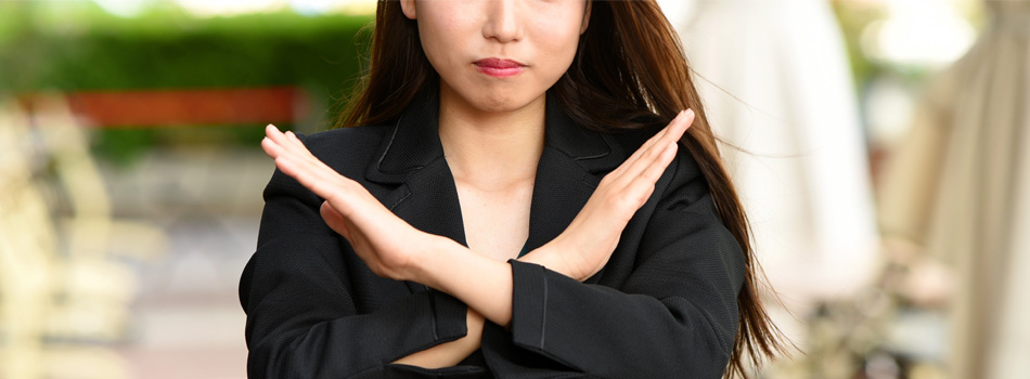 手で×を作る女性