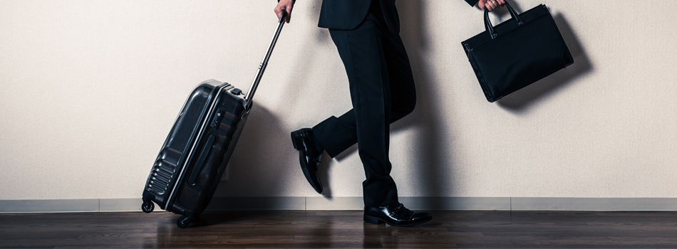 キャリーケースを引くスーツ姿の男性