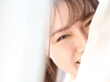 カーテンの隙間から顔を覗かせる笑顔の女性