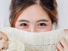 セーターで顔の下半分を画している女性