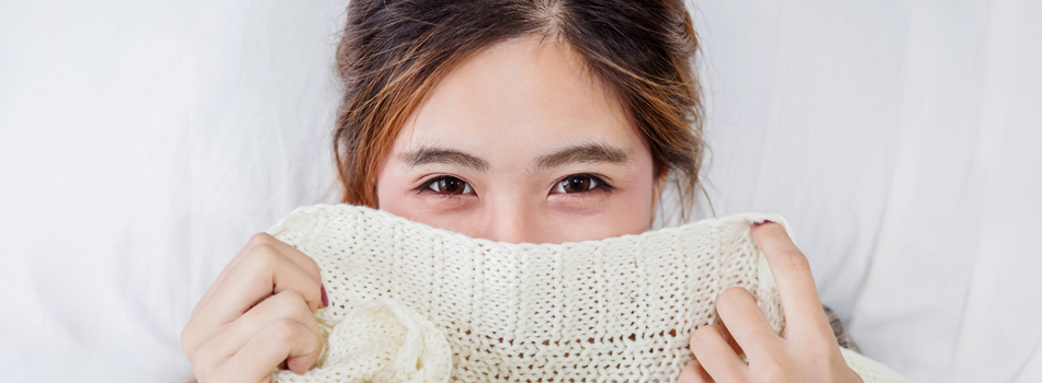 セーターで顔の下半分を画している女性