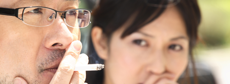 タバコを吸う男性と、怪訝な顔をする女性