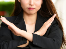 胸元で×マークを作る女性