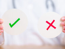 チェックマークと、×マークの札を持ったお医者さん