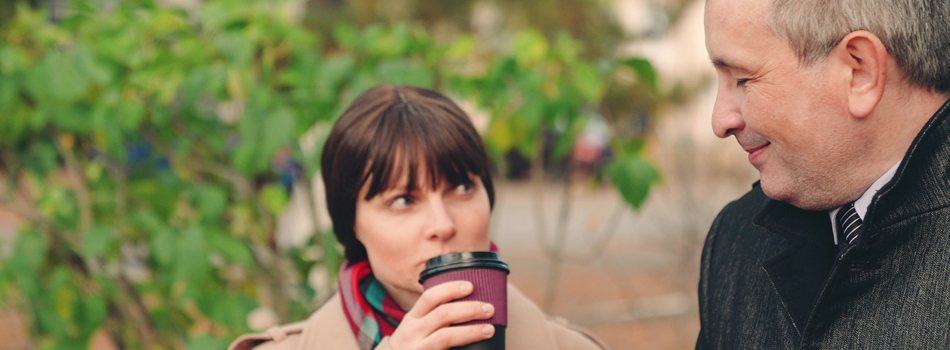 笑顔の初老男性と、男性をコーヒーを飲みながら見つめている女性