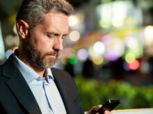 外でスマートフォンを見ているカッコイイ男性