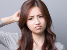 困り顔で頭をかく女性