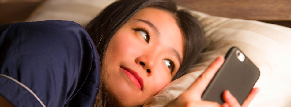 寝る前にスマートフォンを見ている女性