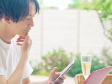 昼、スマートフォンとパソコンを使う男性