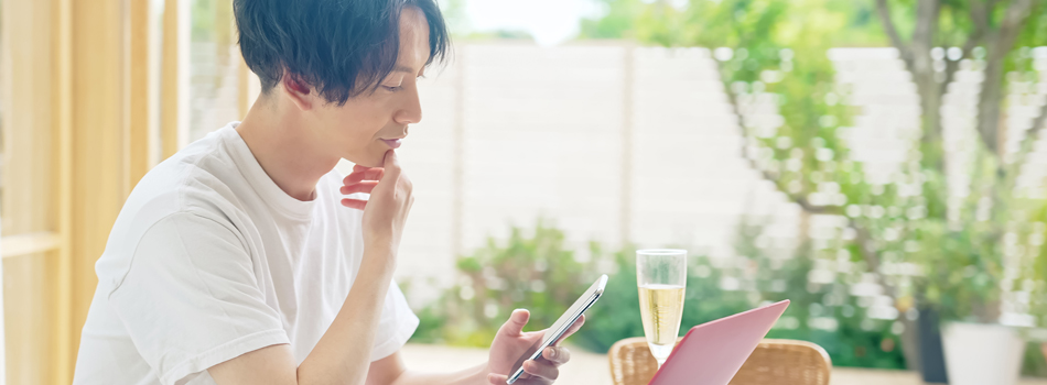 昼、スマートフォンとパソコンを使う男性