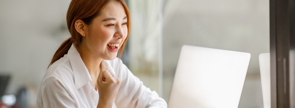 パソコンの前でガッツポーズしている女性