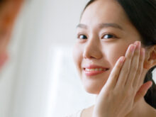 鏡の前で笑顔で化粧をする女性