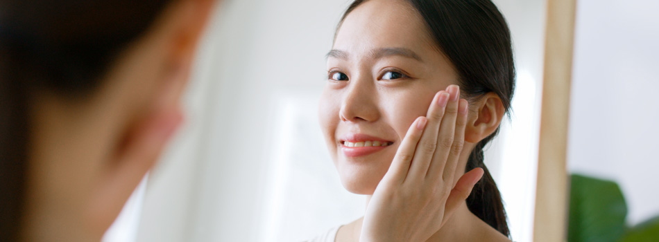 鏡の前で笑顔で化粧をする女性