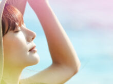 空を見上げ太陽光を浴びている女性